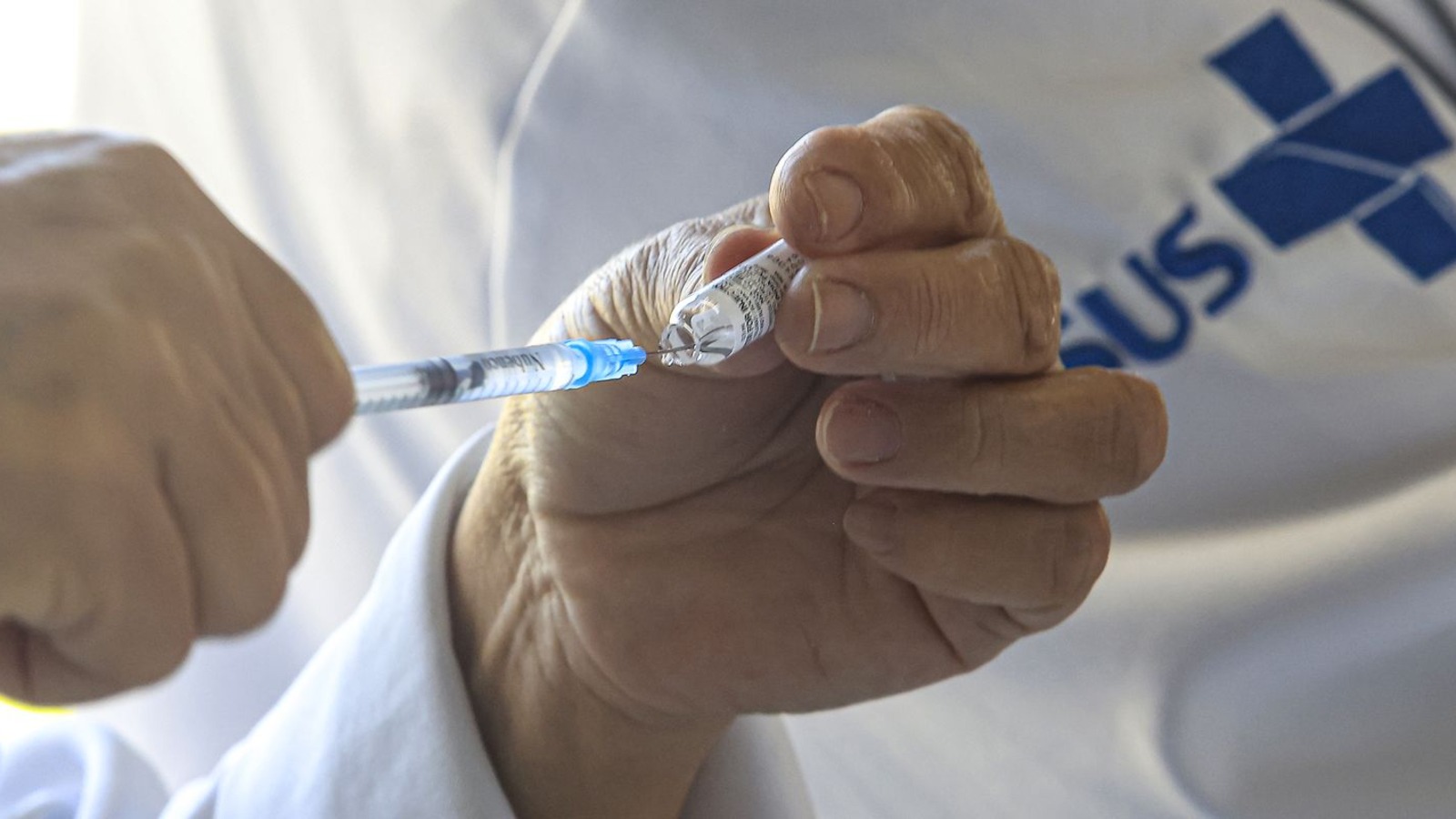 Profissional do SUS prepara dose de vacina em registro fotojornalístico real